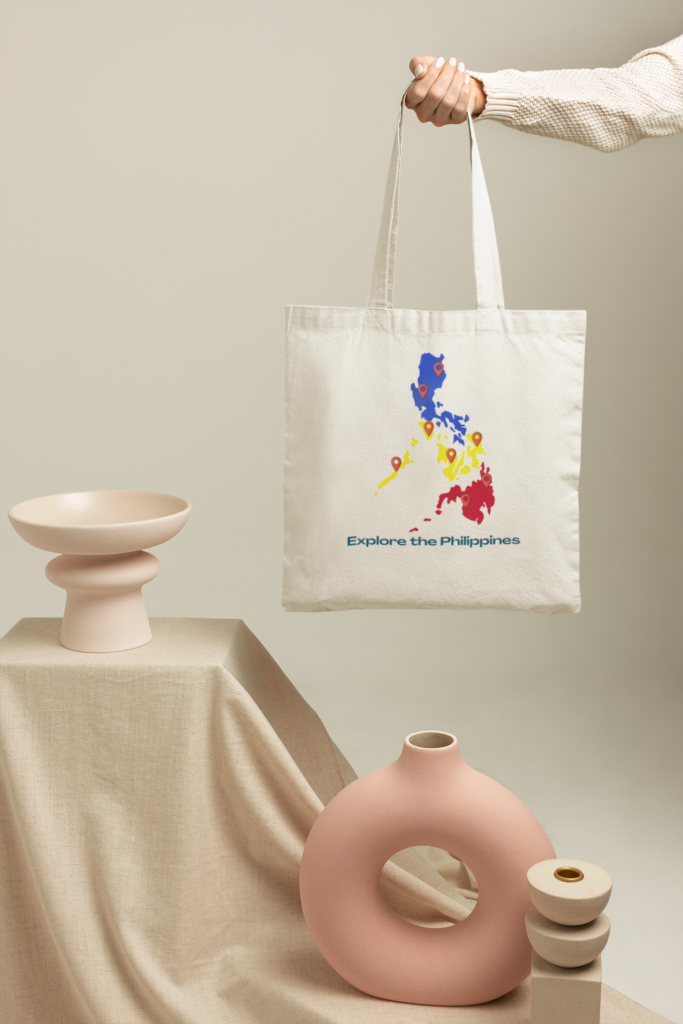 Hand holding a white Philippines map tote bag with Explore the Philippines text in a clean minimalist studio setup